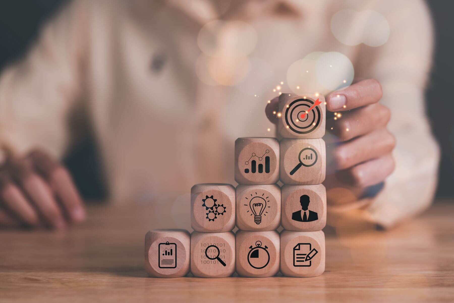 Wooden blocks with business, analytics, strategy and target icons stacked in a pyramid, representing the expanding role of modern marketing leaders.